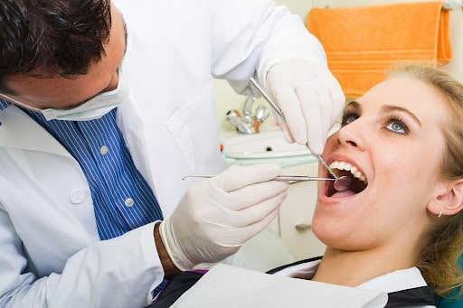 Dentist performing a professional teeth cleaning for a patient during a routine dental exam